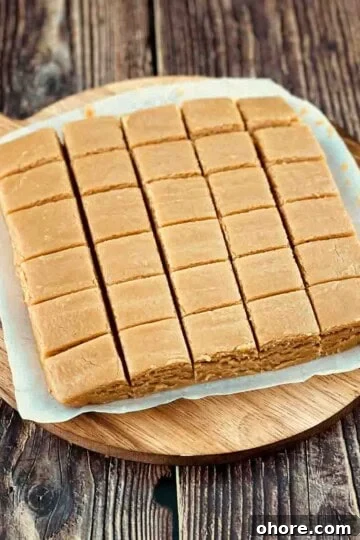 Creamy peanut butter fudge cut into small squares on a round cutting board.