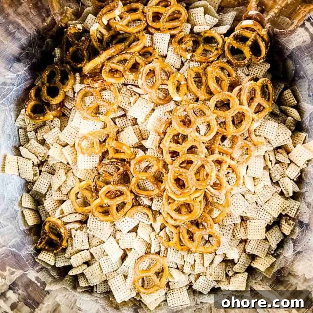 Valentine’s Puppy Chow: Festive Chocolate-Covered Snack Mix Recipe 4 The pretzels and Chex cereal in a large stainless steel mixing bowl.