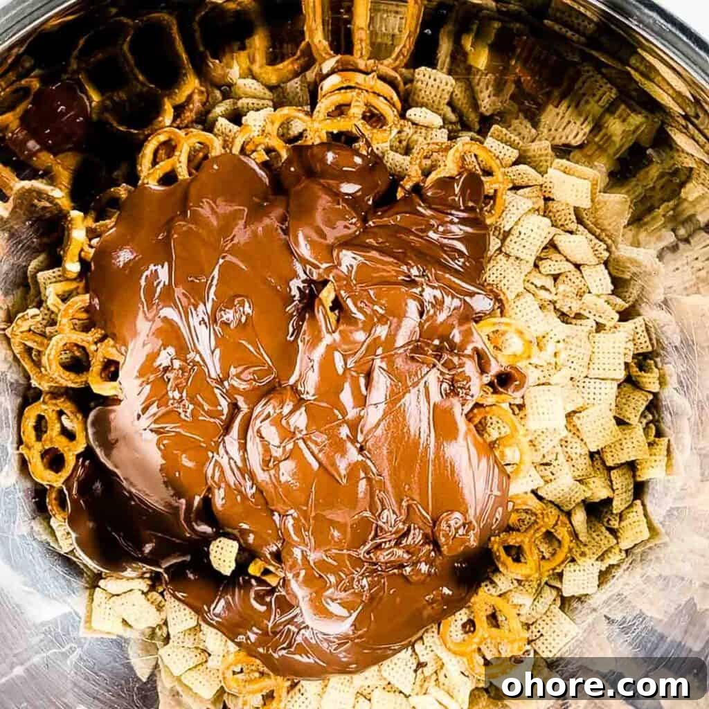 Valentine’s Puppy Chow: Festive Chocolate-Covered Snack Mix Recipe 6 The melted peanut butter mixture poured on top of the Chex and pretzels in the mixing bowl.