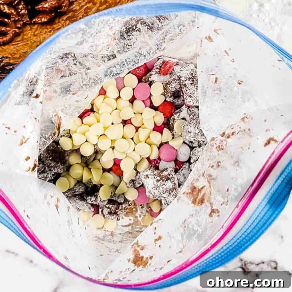 Valentine’s Puppy Chow: Festive Chocolate-Covered Snack Mix Recipe 7 The Valentine's M&Ms and white chocolate chips added to the icing sugar and Chex mixture in a plastic bag.