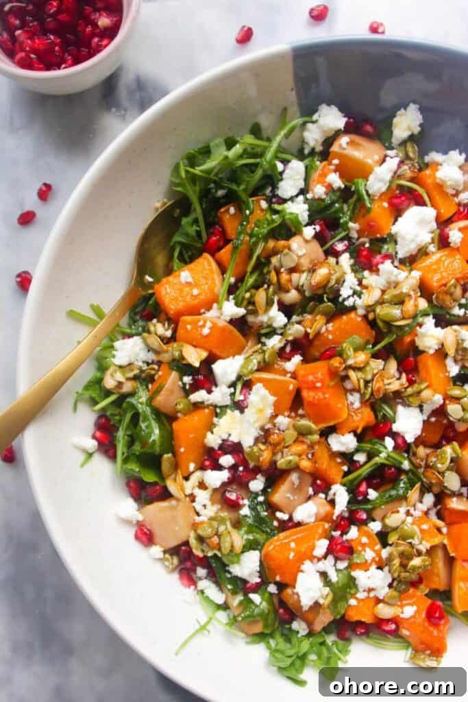 Crispy Rice Chicken Caesar Salad Recipe 12 Large white and blue serving bowl with colourful butternut squash salad inside and pomegranate seeds on the side.