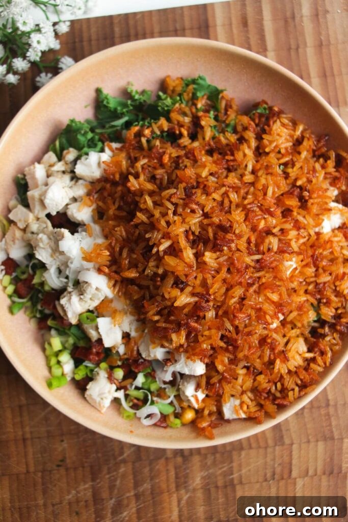Crispy Rice Chicken Caesar Salad Recipe 8 Crispy parmesan rice on top of chicken Caesar salad in pink bowl.