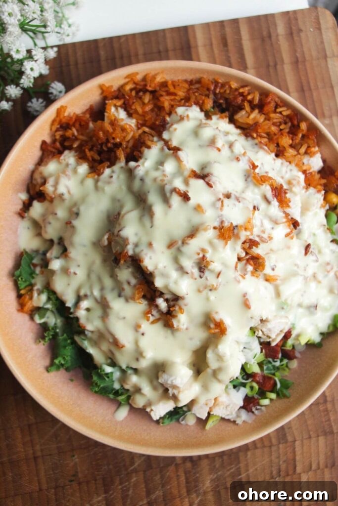 Crispy Rice Chicken Caesar Salad Recipe 9 Caesar dressing poured over crispy rice salad in pink bowl.