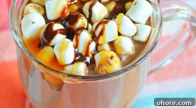 Boozy hot chocolate in a mug, decorated with marshmallows and chocolate caramel syrup