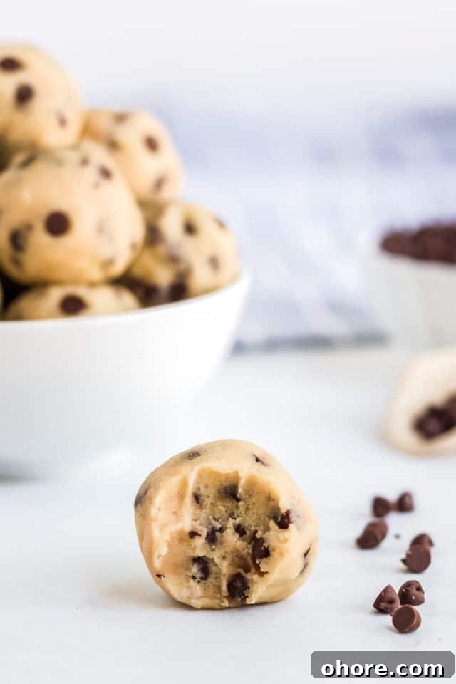 Keto Cookie Dough Fat Bombs Recipe for Low-Carb Snacking 5 half chewed cookie dough ball with cookie dough balls in a bowl in the back