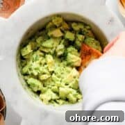 Fresh, chunky 4-ingredient guacamole in a bowl with a crispy tortilla chip ready for dipping