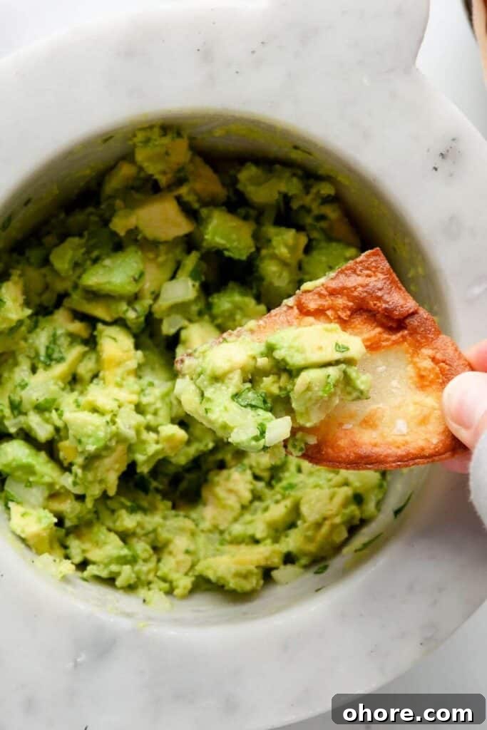 Close-up of easy 4-ingredient guacamole scooped on a crispy chip showing chunky texture