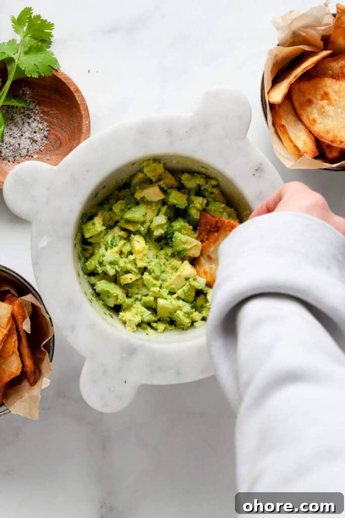 Crispy tortilla chip being dipped into fresh, healthy guacamole made with just 4 ingredients