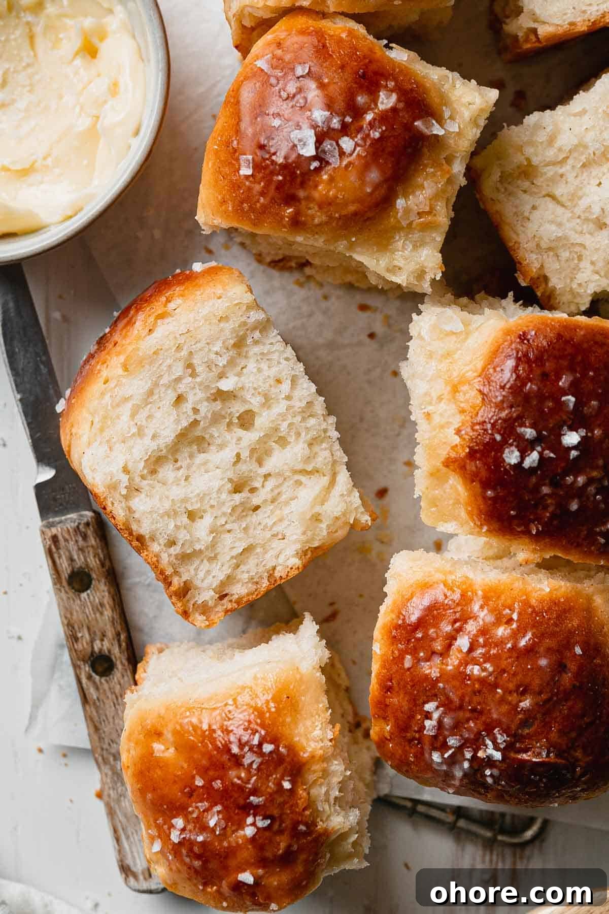 Soft Gluten-Free Dinner Rolls Recipe — Classic Homemade Rolls 2 Fluffy gluten-free dinner rolls on parchment, one on side showing airy texture.