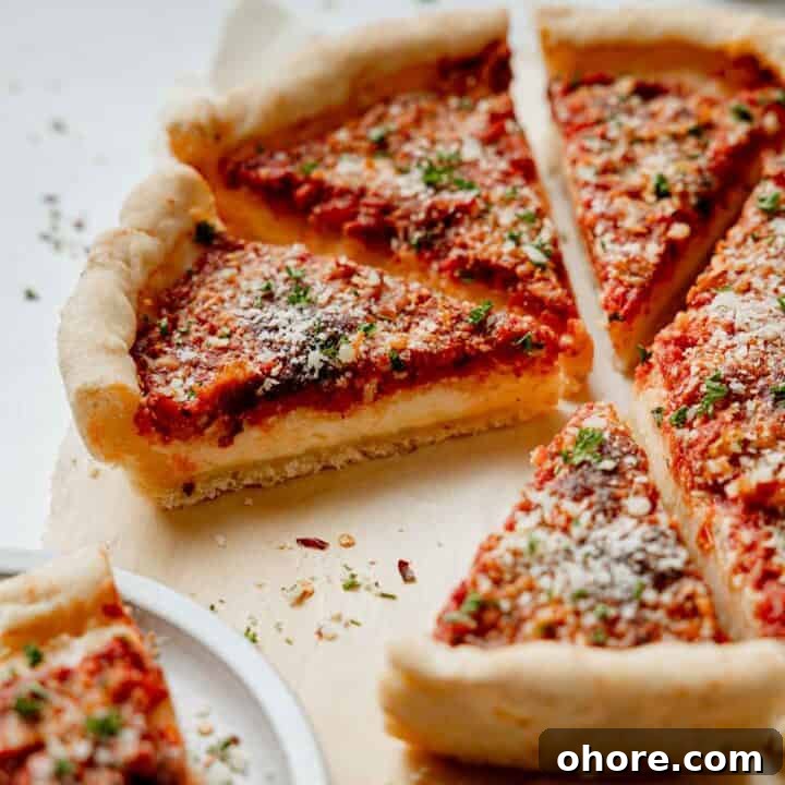 Gluten free Chicago deep dish pizza with sauce on top, sliced and resting on parchment paper.