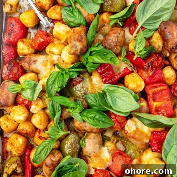 One-Pan Baked Creamy Broccoli Gnocchi Recipe 12 Closeup image of the top of a sausage and peppers sheet pan gnocchi dinner with lots of fresh basil on top.