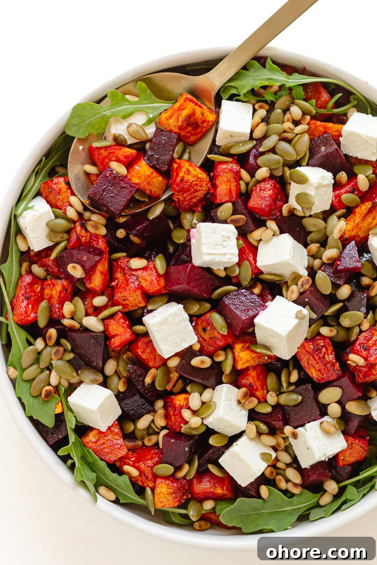 Roasted Pumpkin and Beetroot Salad with Feta and Toasted Seeds 2 Roasted pumpkin and beetroot salad in a serving bowl with gold colored serving spoon.