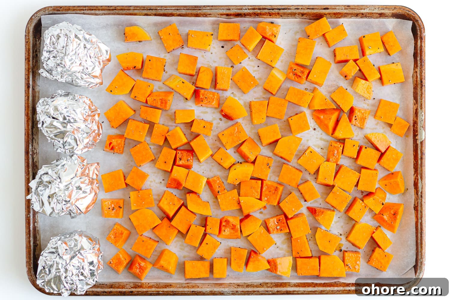 Roasted Pumpkin and Beetroot Salad with Feta and Toasted Seeds 5 Cubed pumpkin and beets wrapped in foil on a lined baking sheet.