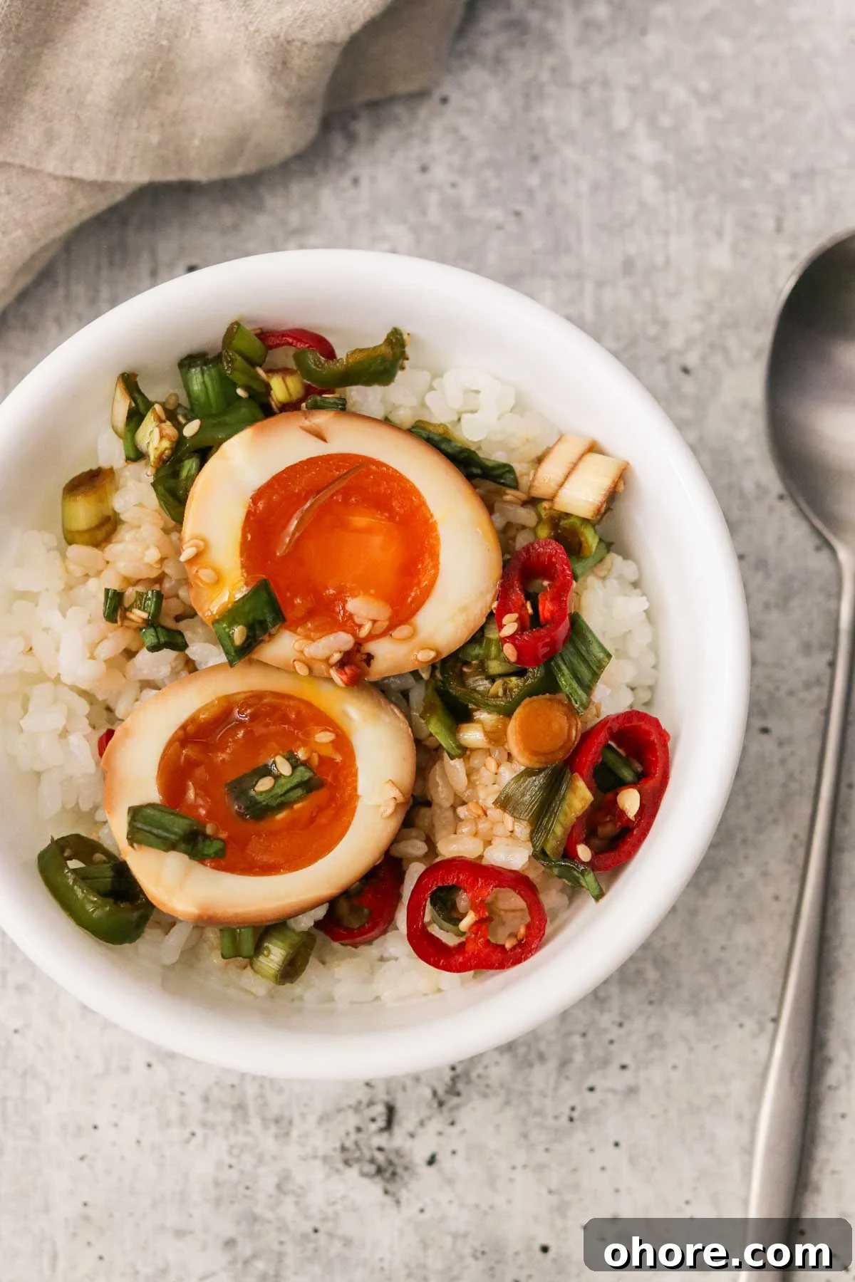 two marinated mayak eggs served over rice in a white bowl