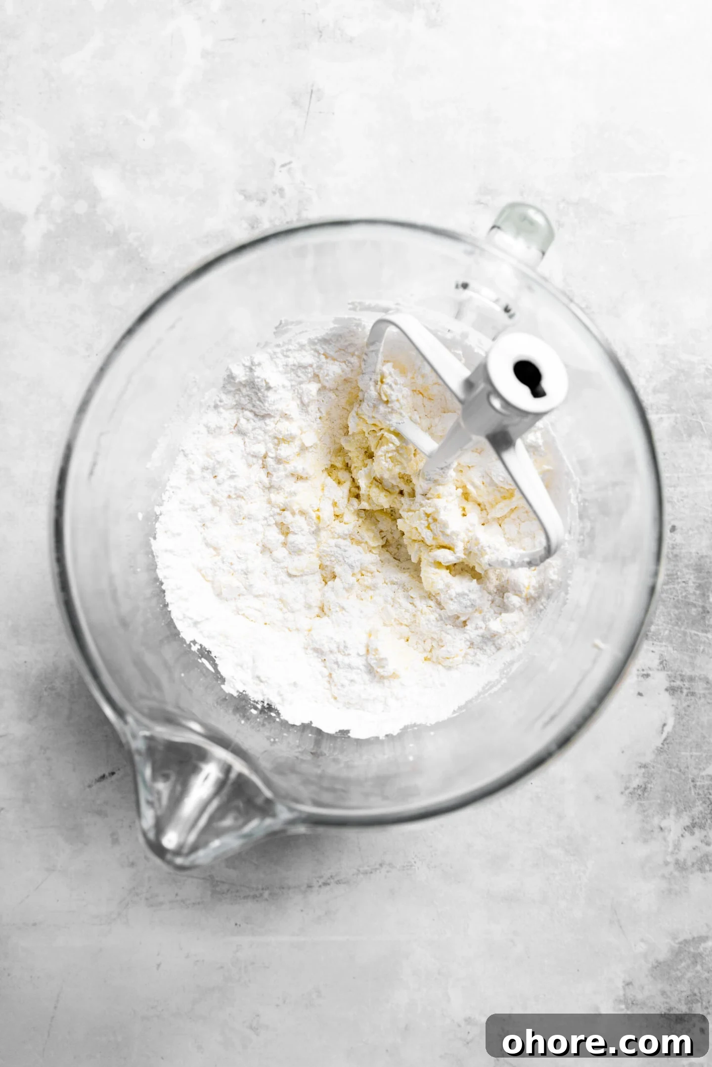 Cream Cheese Frosting with 5 Simple Ingredients 4 Powdered sugar being added and beaten into butter and cream cheese mixture.