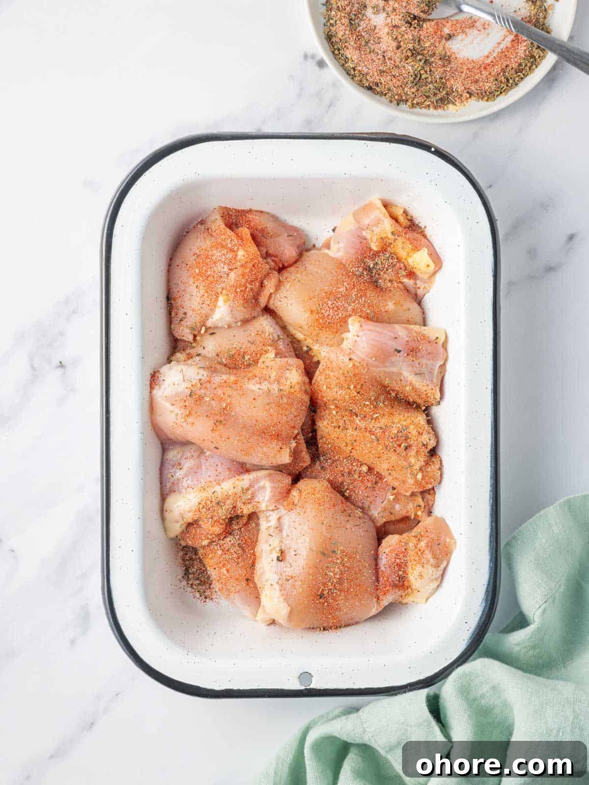 Crispy Air Fryer BBQ Chicken Recipe for Juicy, Quick Dinners 4 Seasoning raw chicken thighs in a dish.
