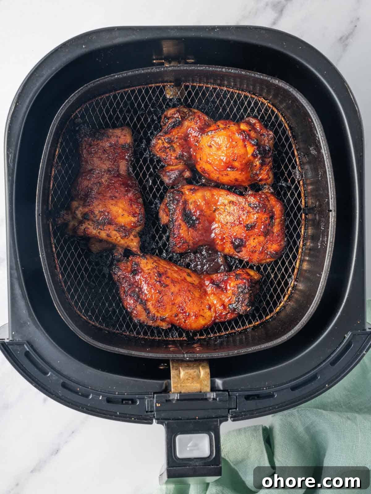 Crispy Air Fryer BBQ Chicken Recipe for Juicy, Quick Dinners 6 Finished bbq chicken thighs resting in an air fryer basket.