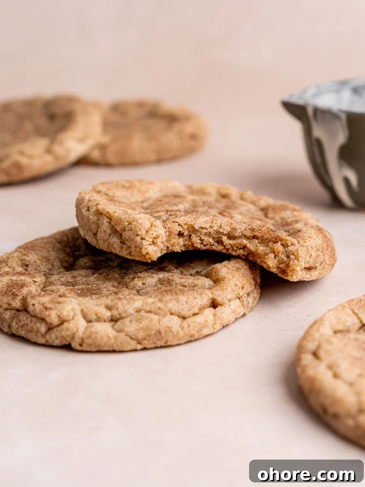 Stacked snickerdoodle cookies with a bite taken out of the top cookie.
