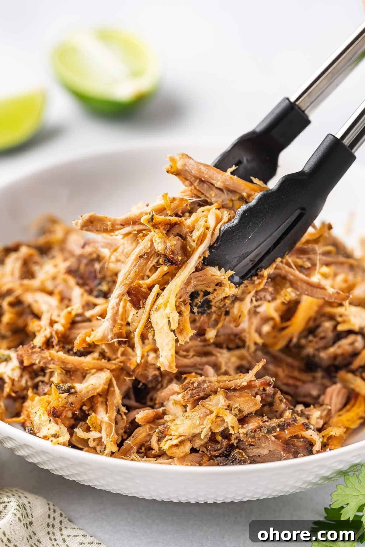 Authentic Slow Cooker Carnitas Recipe for Tender Shredded Pork 2 A pair of tongs lifting up some shredded slow cooker carnitas.