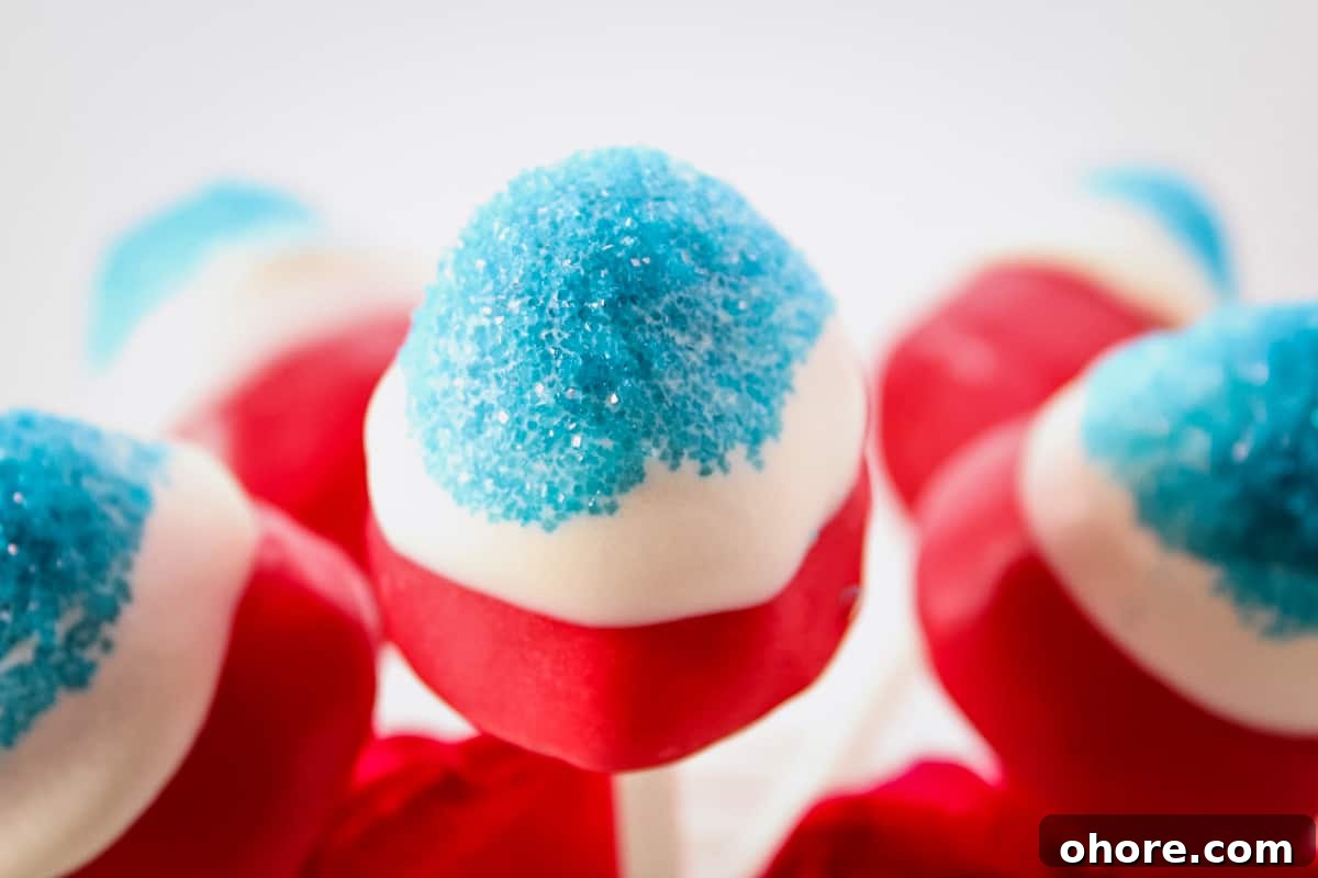 Sparkling Strawberry Firecracker Pops: Patriotic Summer Treats 4 Close up of red and white candy coated strawberry with blue sanding sugar on the top.
