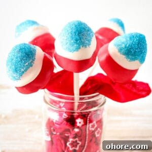 Sparkling Strawberry Firecracker Pops: Patriotic Summer Treats 6 Red, white, and blue covered strawberries on sticks in a mason jar.