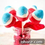 Sparkling Strawberry Firecracker Pops: Patriotic Summer Treats 7 Red, white, and blue covered strawberries on sticks in a mason jar.