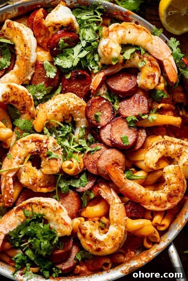 Cajun Shrimp and Creamy Cheddar Grits Recipe 11 up close photo of cajun shrimp and sausage pasta in a pan.