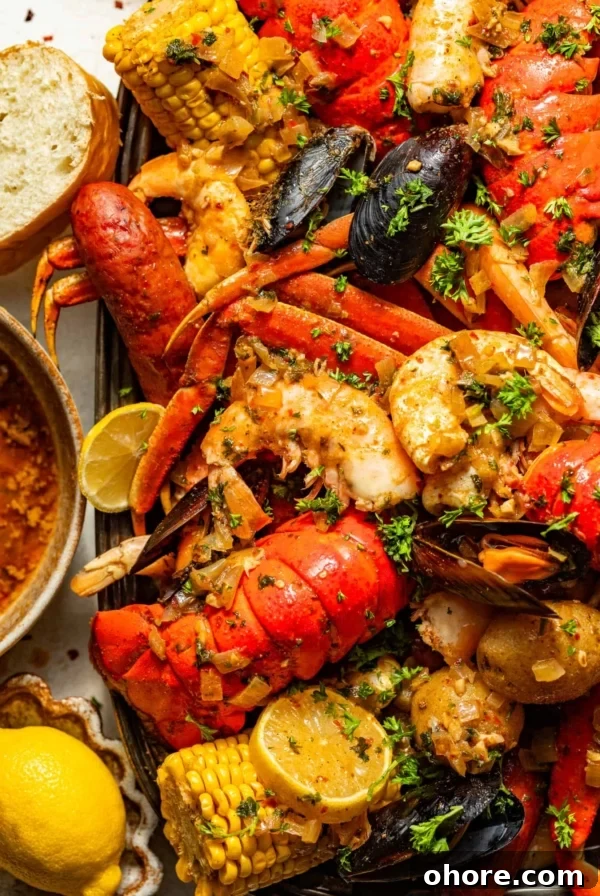 Cajun Shrimp and Creamy Cheddar Grits Recipe 9 cajun seafood boil recipe on a large serving tray next to a bowl of seafood boil sauce, bread, and sliced lemons