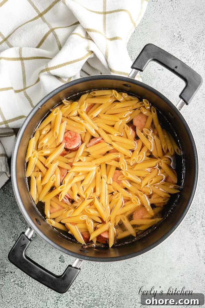Creamy Kielbasa Pasta Recipe with Garlic Parmesan Sauce 4 Noodles, broth, and water added to the pot.