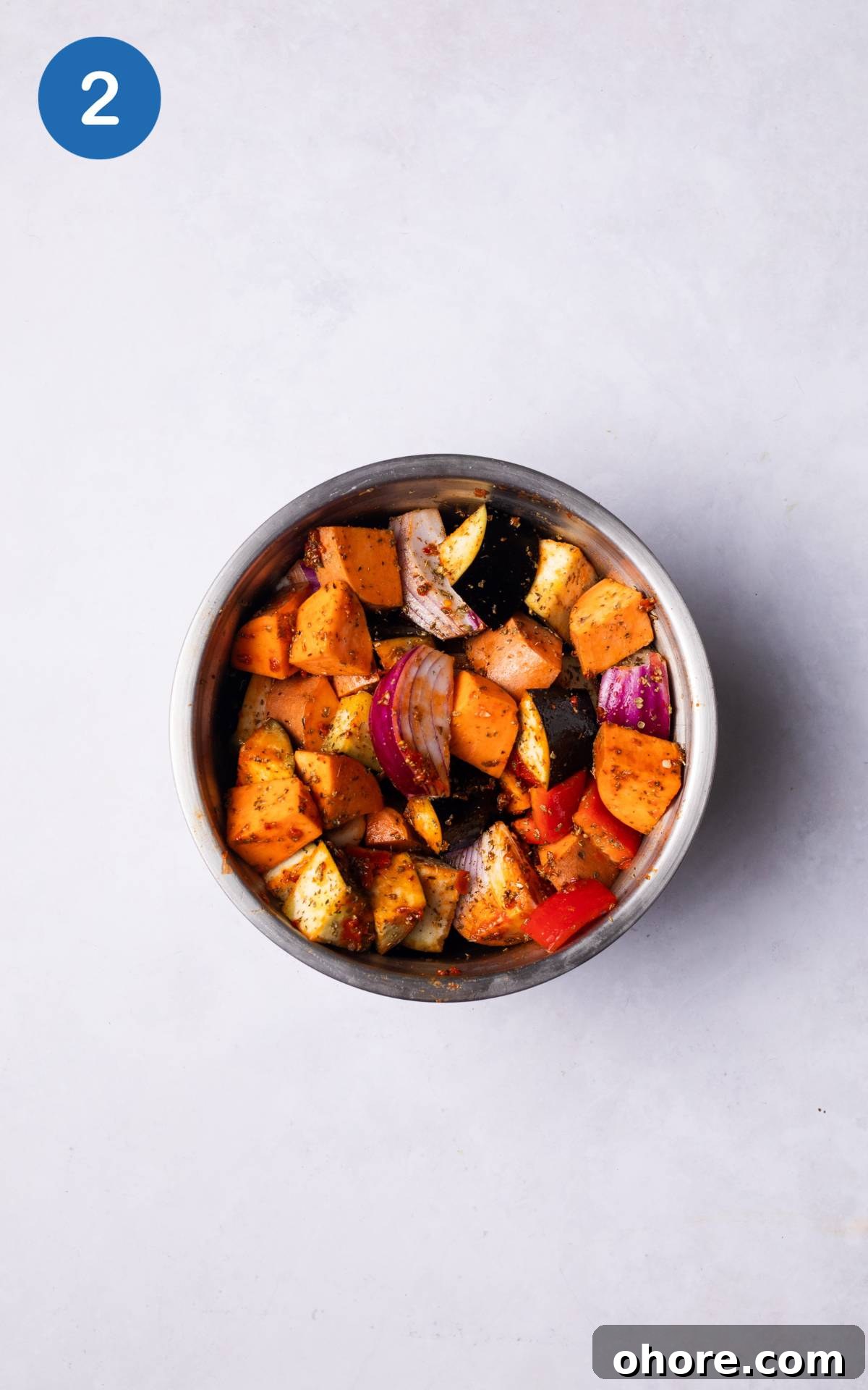 covering the vegetables with harrisa paste and spices in a bowl.