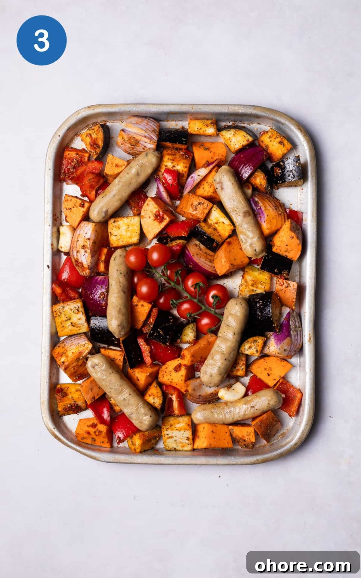 Sausages added to the tray with the vegetables.