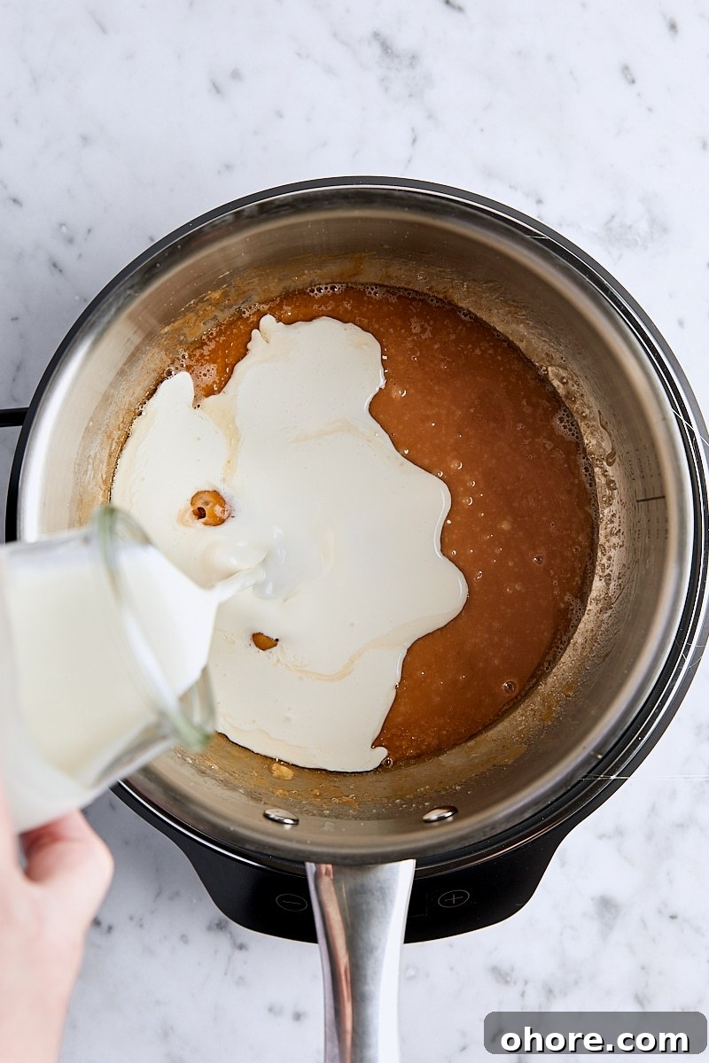 Heavy cream added to caramel mixture in light-colored saucepan