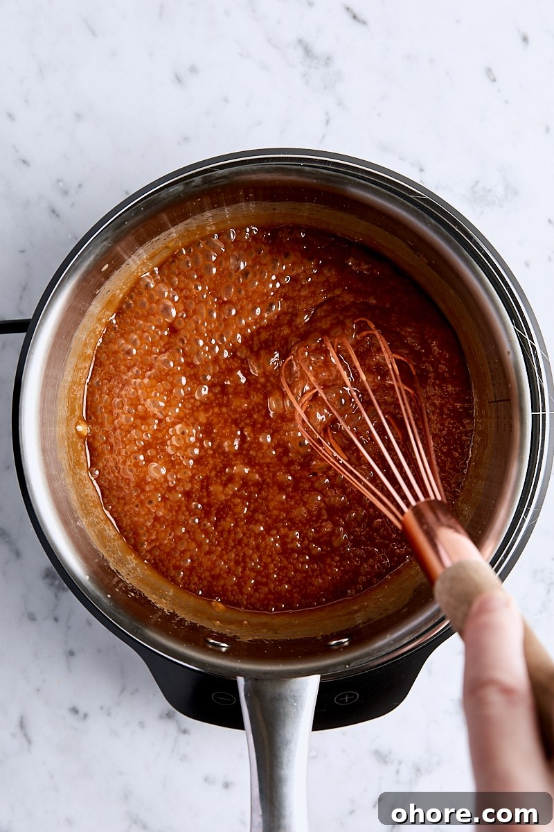 Cream whisked into caramel mixture in light-colored saucepan