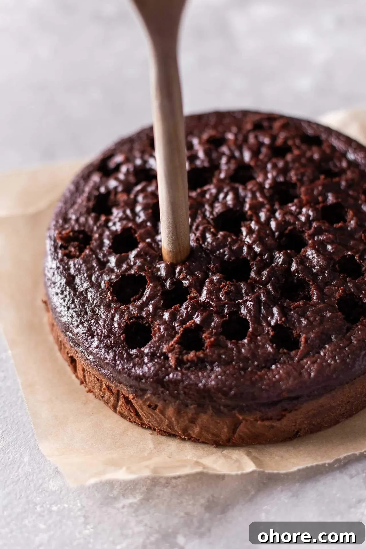 Decadent Hot Chocolate Poke Cake Recipe for Chocolate Lovers 9 hot chocolate cake with wooden spoon poking holes on surface of cake