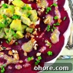 Bird's eye view of a beet carpaccio salad topped with avocado and a chia dressing