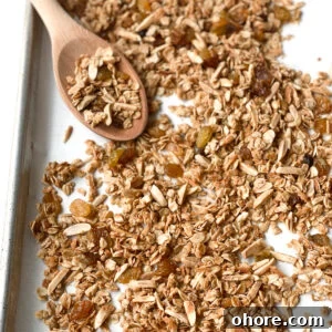 Easy almond coconut granola on a baking sheet with a wooden spoon.