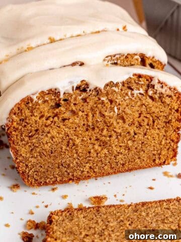 A loaf of spice cake with brown butter cream cheese frosting cut into slices.