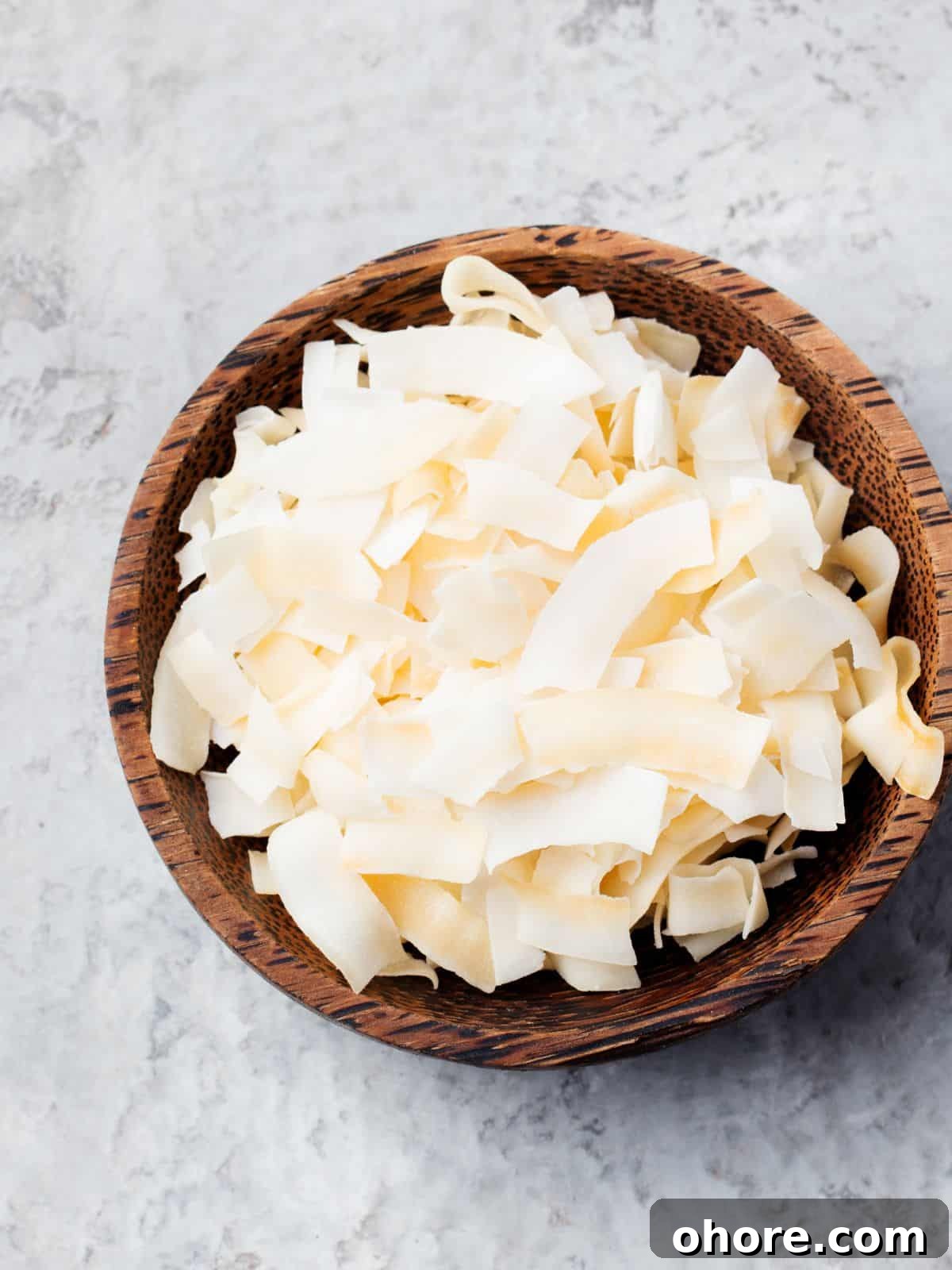 Keto-Friendly Travel Snacks for Low-Carb Trips 5 A wooden bowl brimming with wide, flat, ivory-colored pasta ribbons rests on a light textured surface, evoking a sense of culinary wanderlust akin to discovering new keto travel snacks.