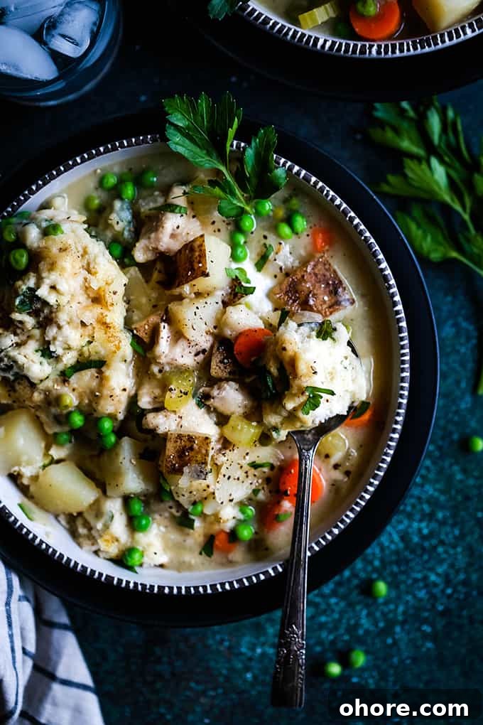 Easy Chicken and Dumpling Soup An overhead shot of a bowl of Easy Chicken and Dumpling Soup on a green speckled surface.