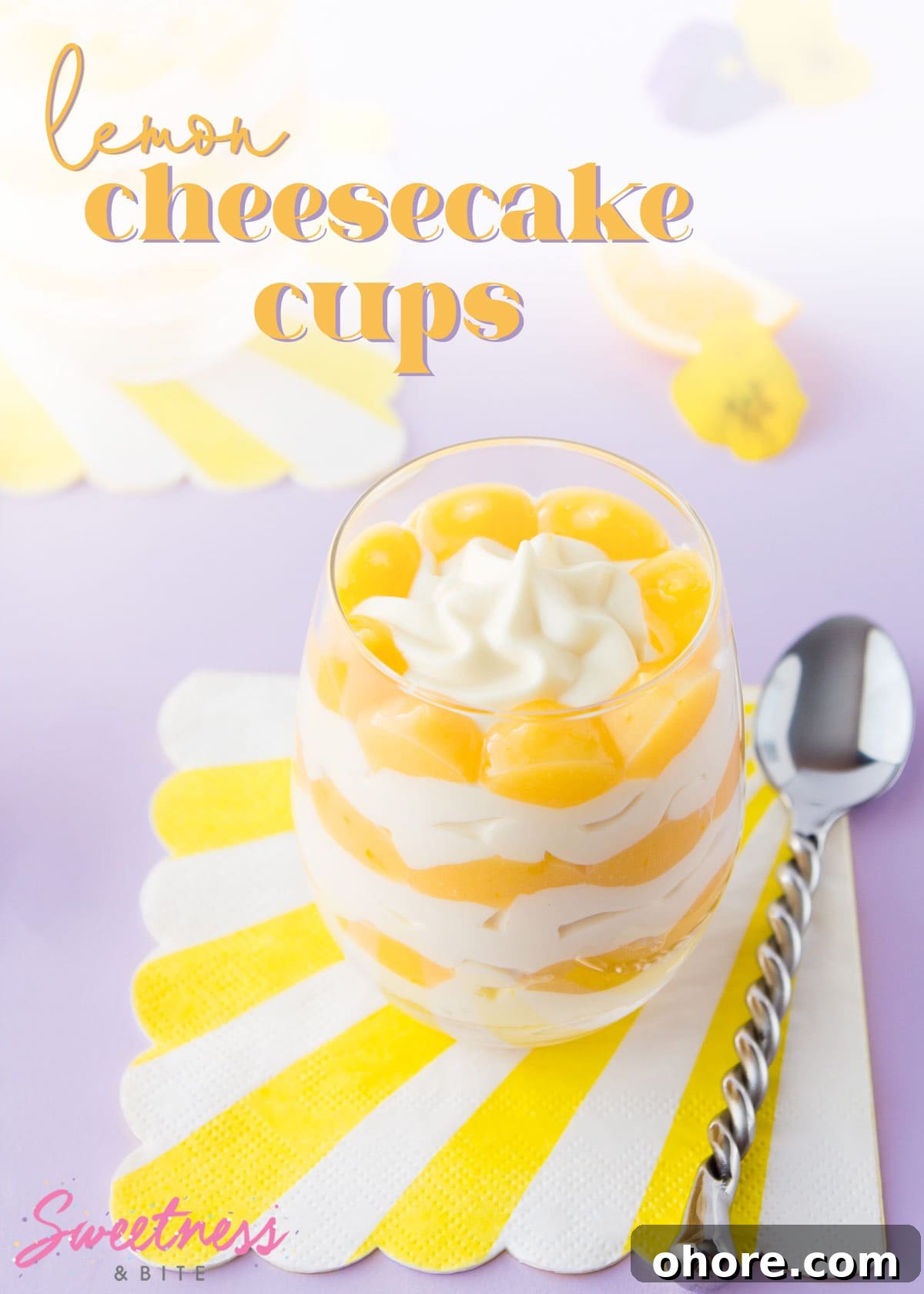 A layered lemon cheesecake in a stemless wine glass, text overlay reads "lemon cheesecake cups".