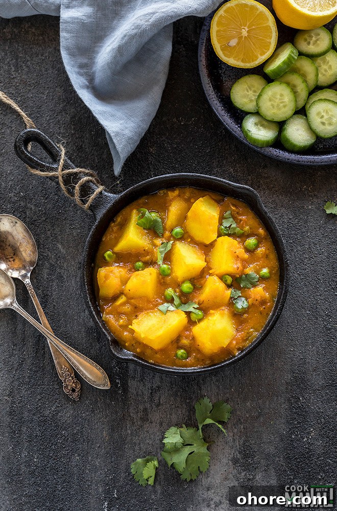 Instant Pot Aloo Matar (Potatoes and Peas Curry) 4 instant pot aloo matar served in a small black skillet with a plate of salad on the side