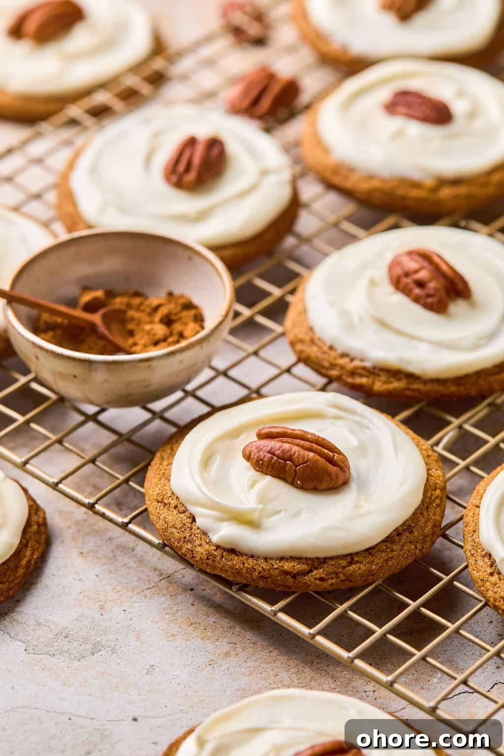 Pumpkin Spice Molasses Cookies Recipe for Cozy Fall Baking 2 Molasses cookies on cooling rack with icing and pecan on top.