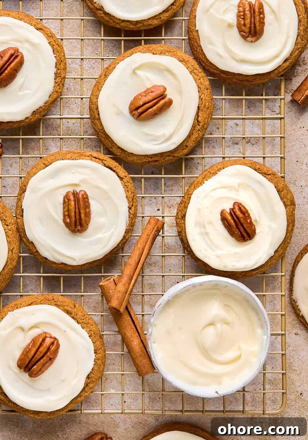 Pumpkin Spice Molasses Cookies Recipe for Cozy Fall Baking 15 Maple cream cheese frosted pumpkin spice molasses cookies on cooling rack with cinnamon sticks.