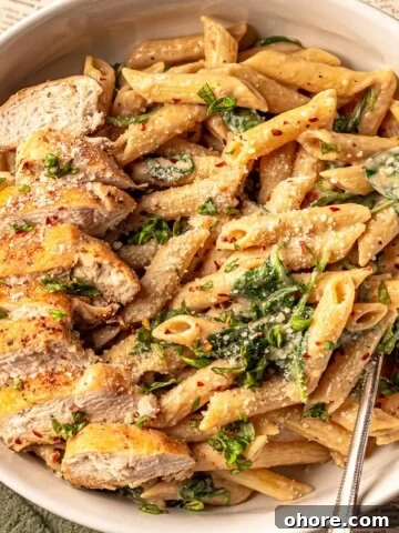 A bowl of pasta topped with sliced chicken.