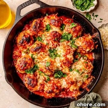 Baked Chicken Parmesan Meatballs Recipe That Melts in Your Mouth 12 Meatballs in a cast iron skillet topped with mozzarella cheese and parsley.