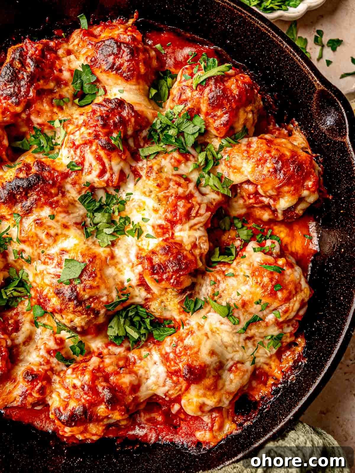 Baked Chicken Parmesan Meatballs Recipe That Melts in Your Mouth 7 Chicken parmesan meatballs topped with mozzarella cheese in a skillet.