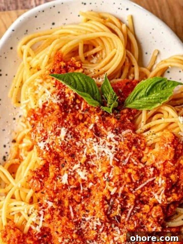 Chicken bolognese on top of spaghetti.