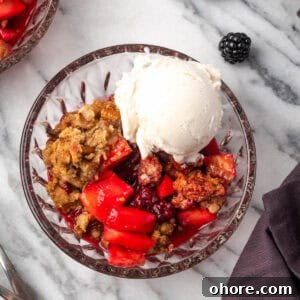 Apple & Blackberry Crumble Recipe: Rustic Autumn Dessert 11 A serving of apple blackberry crumble in a glass bowl topped with vanilla ice cream.