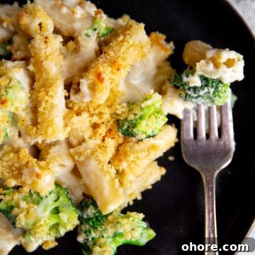 Close up of a serving of creamy baked pasta on a plate with a fork.