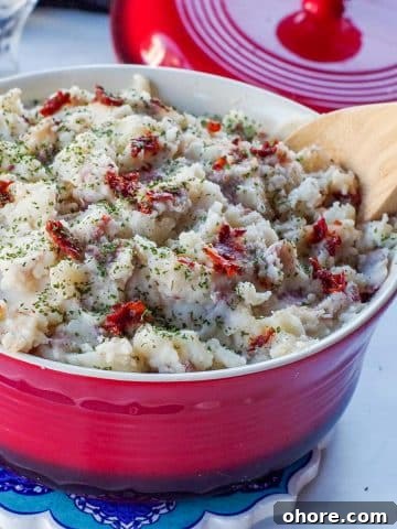 Chipotle mashed potatoes in a red serving bowl with a wooden spoon.